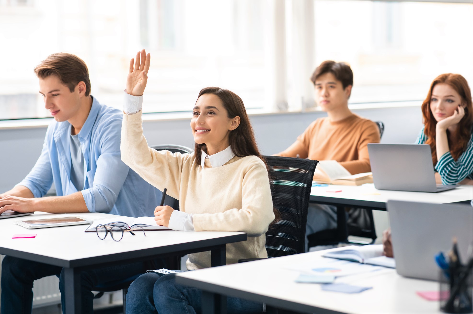 Portrait of female student raising hand at classroom